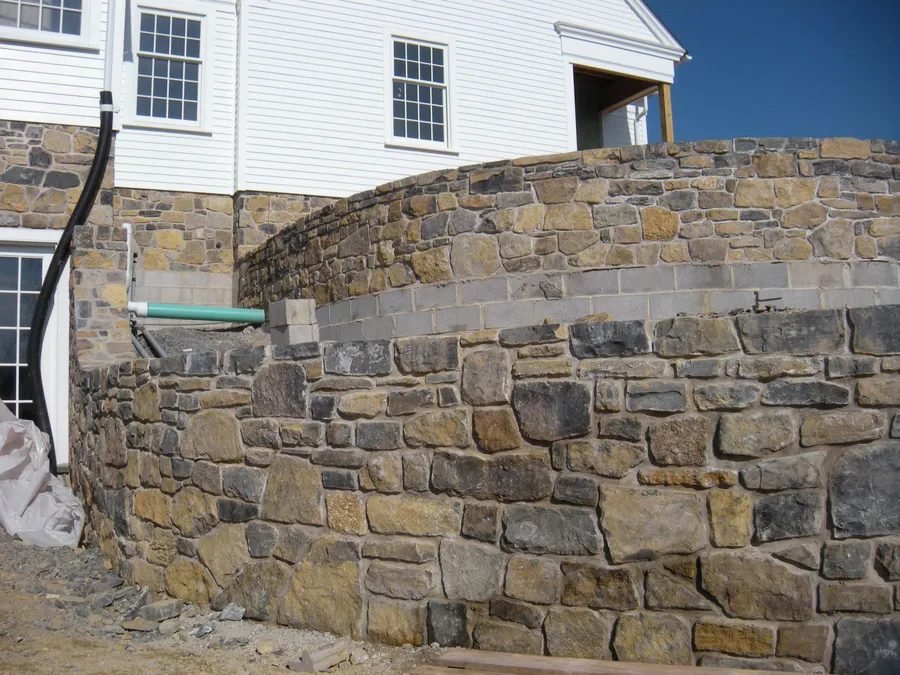 A curved natural stone retaining wall built by Pyle Bros.
